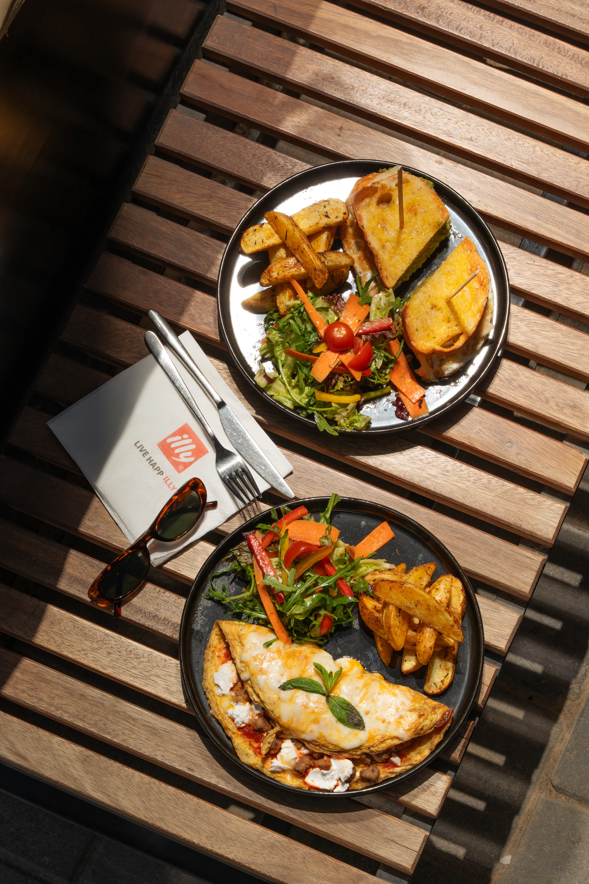 Outdoor illy café table with salads, fries and sunglasses