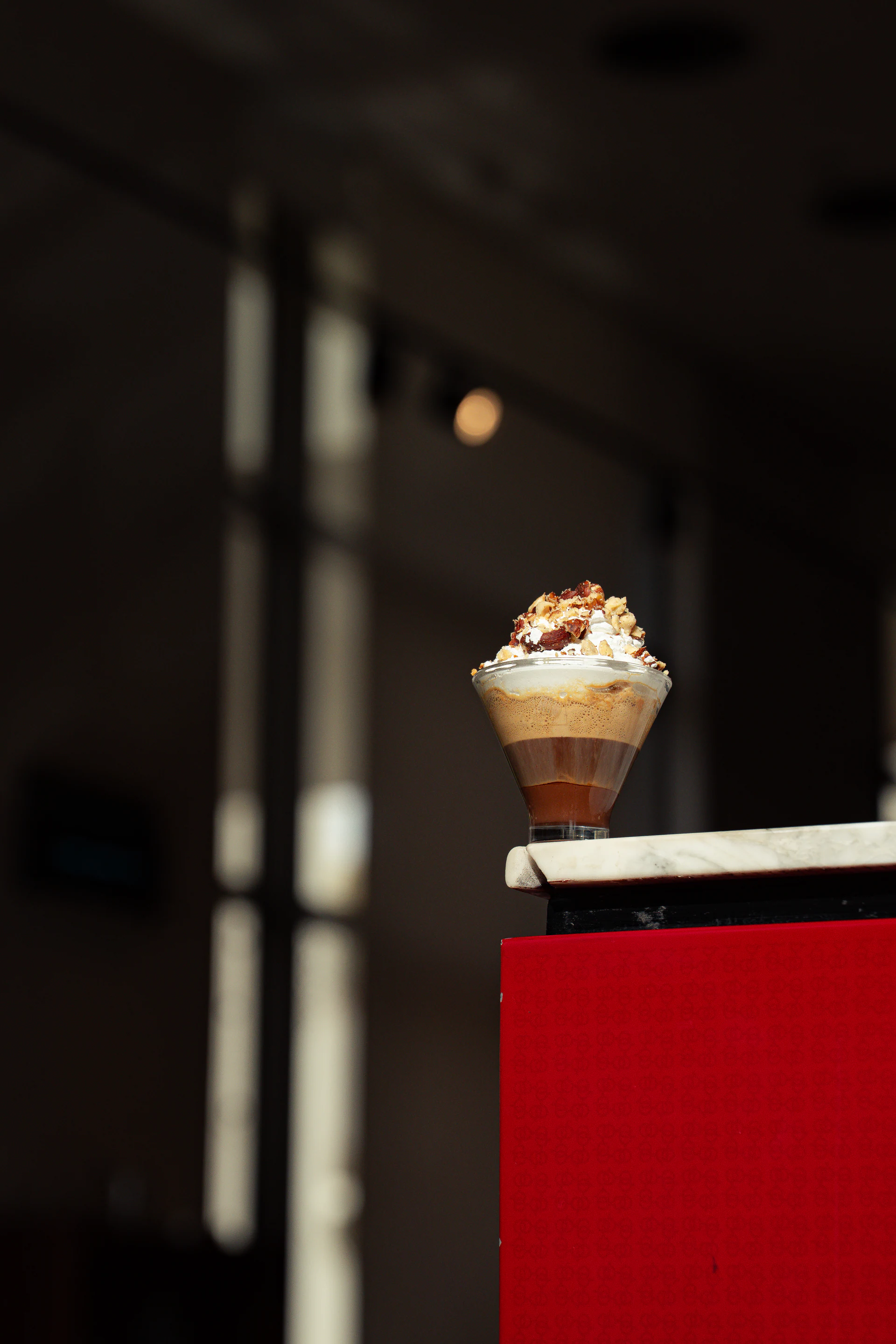 Layered illymisu dessert displayed on a sunlit café counter