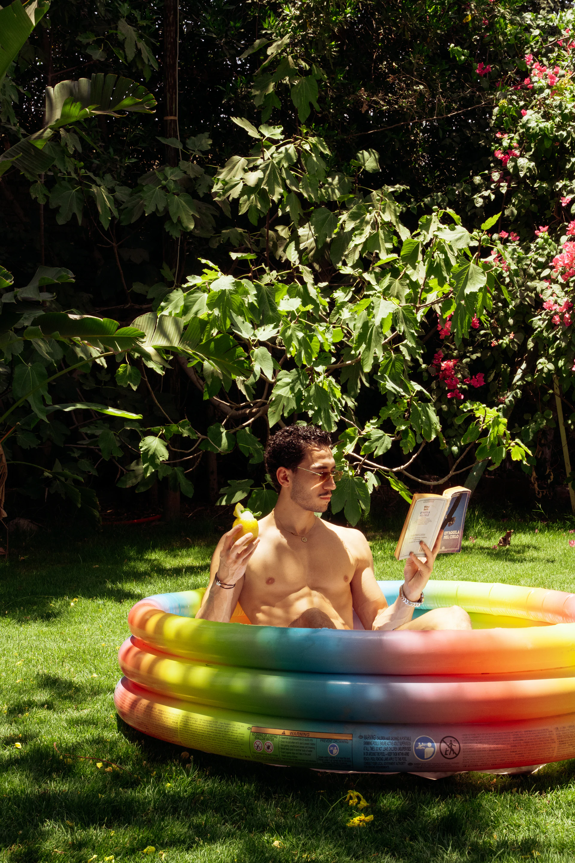 Man relaxing in a garden pool with a book and frozen drink