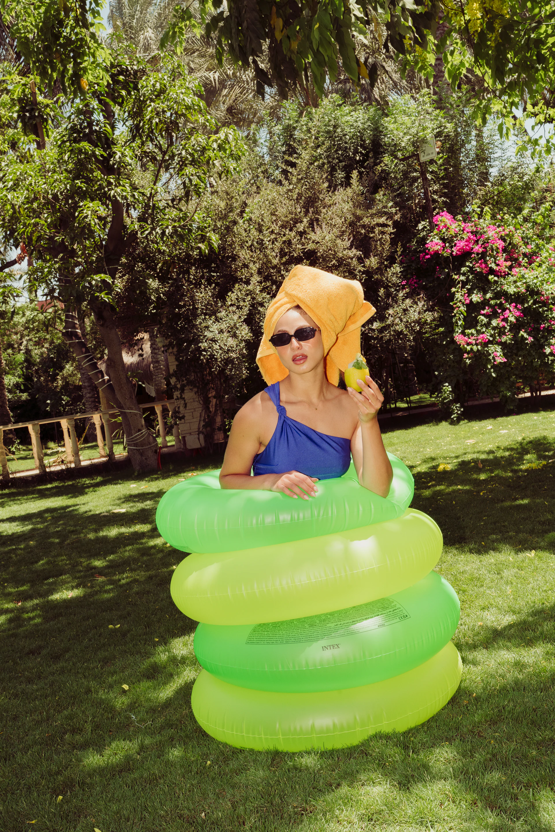 Woman posing inside a bright green inflatable ring in the garden