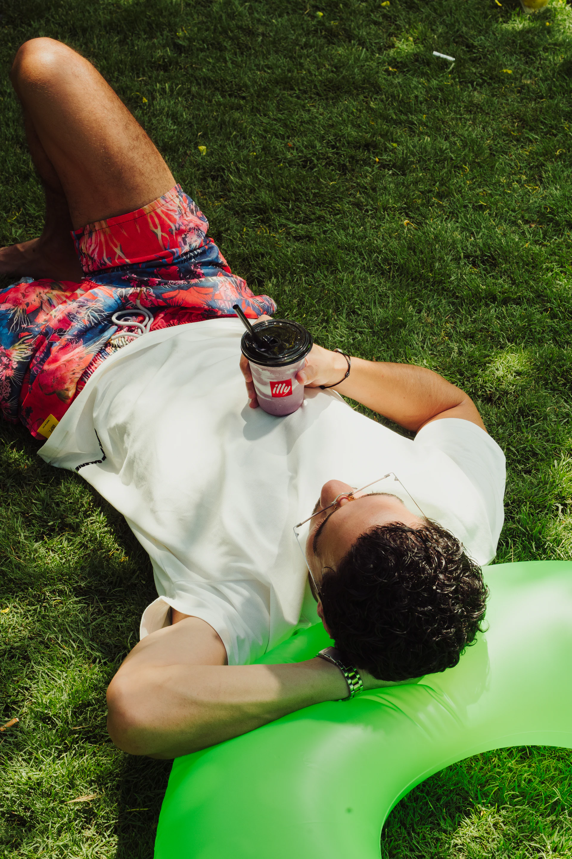 Man relaxing on a green inflatable ring with an illy drink