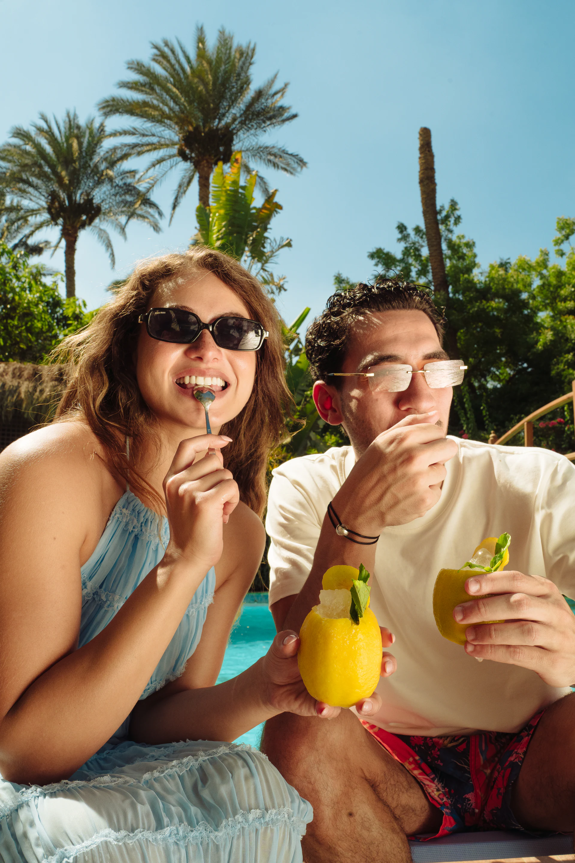 Two friends enjoying lemon sorbet drinks beside the pool