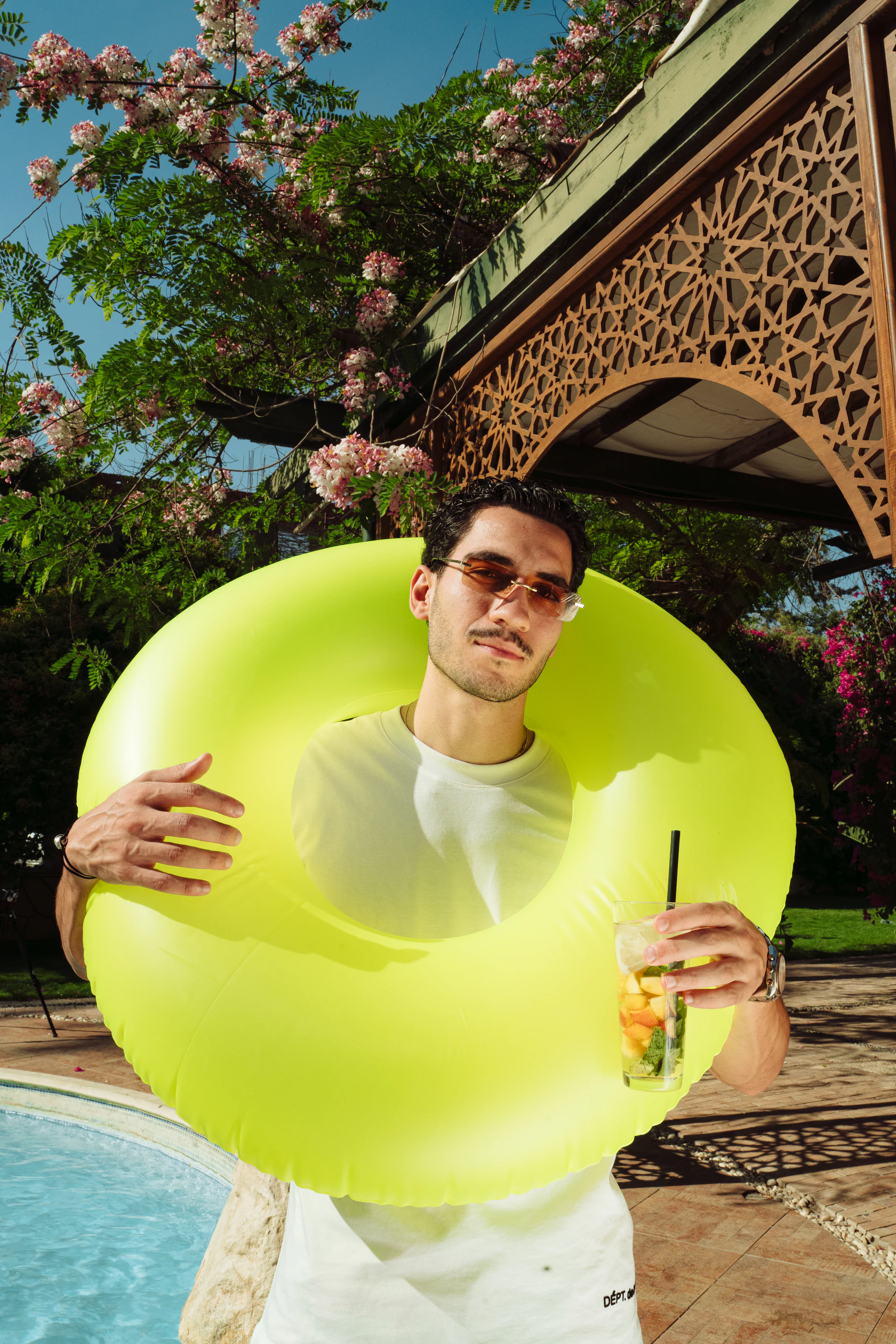 Man carrying a green swim ring and an illy summer drink