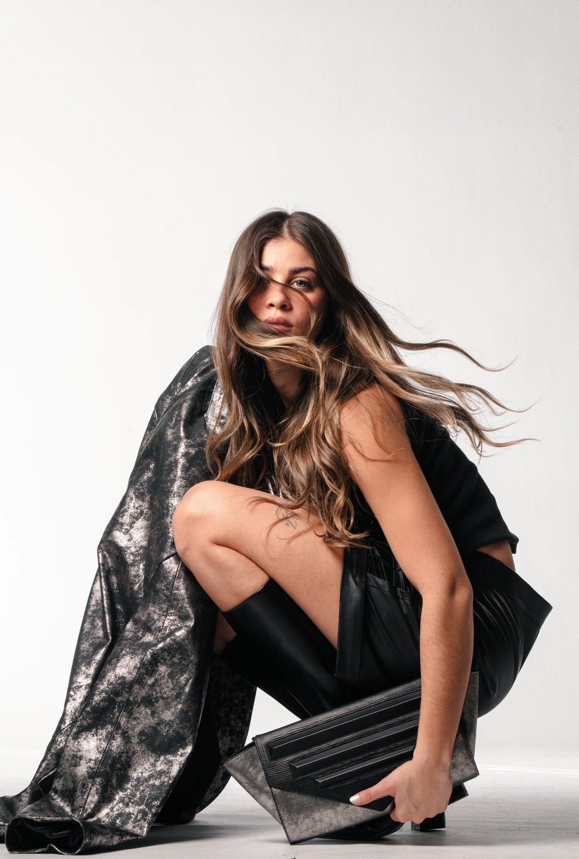 Leopelle model styled with a metallic leather coat and clutch